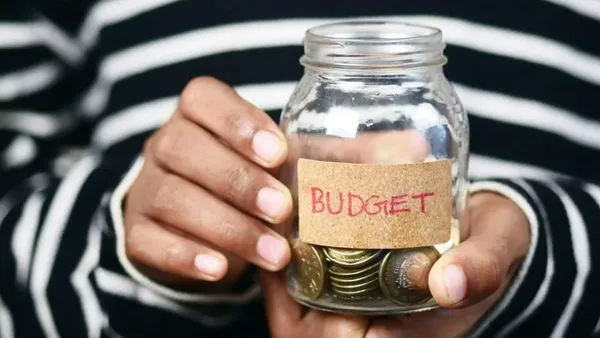Hands holding a coin jar labeled BUDGET – Zidika Consulting Kenya