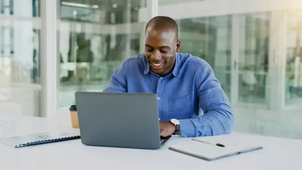 Smiling man building a financial model on his laptop in a Nairobi office – Zidika Consulting, Kenya
