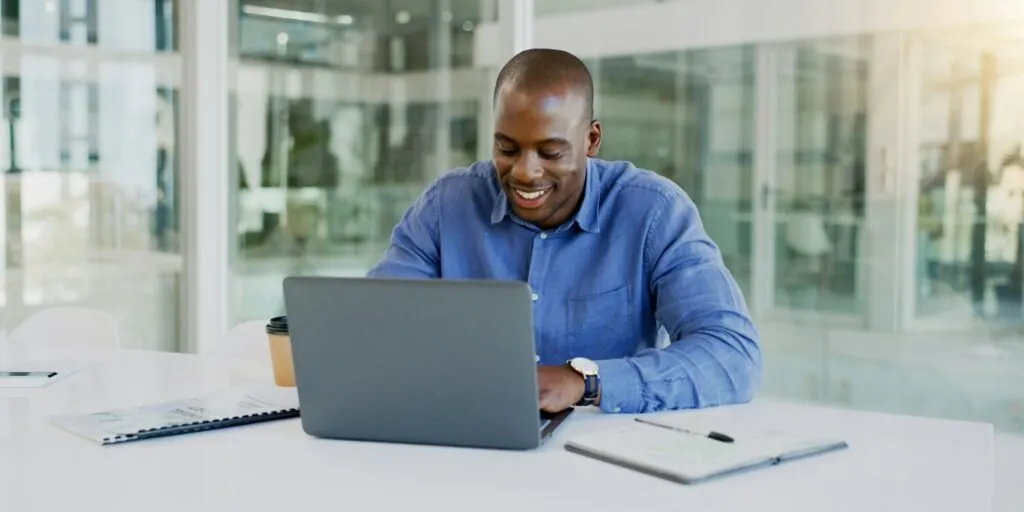 Smiling man building a financial model on his laptop in a Nairobi office – Zidika Consulting, Kenya
