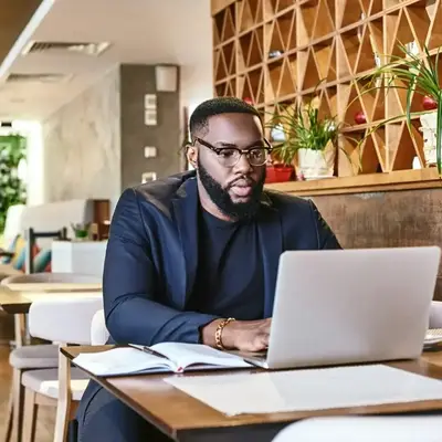 Man working on funding models at a café in Kenya – Zidika Consulting